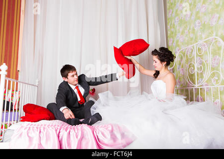 Fröhliche junge Hochzeit paar Kissen Kämpfe im Bett zu Hause Stockfoto