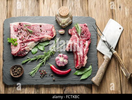 Rohes Rindfleisch Steaks mit Gewürzen auf dem schwarzen Schneidebrett. Stockfoto