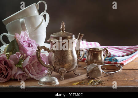 Teekanne mit trockenen Tee und Geschirr auf einem Holztisch Stockfoto