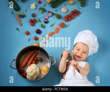 Baby Boy in Koch Hut mit Kochen Pfanne und Gemüse Stockfoto