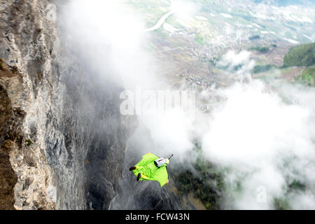 Diese wingsuit Base Jumper nur verlassen von einer Klippe hinunter ins Tal. Er wird seinen Fallschirm kurz vor der Cloud schlagen. Stockfoto