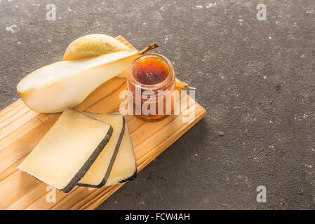 Eine Komposition aus italienischen Pecorino Käsescheiben mit Marmelade und Birnen auf ein Schneidbrett aus Holz Stockfoto