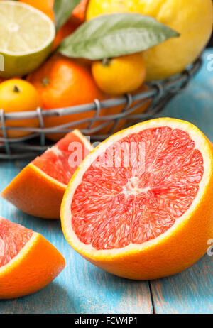 Scheiben von Grapefruit, verschiedene frische Zitrusfrüchte in einem Korb auf einem blauen Hintergrund aus Holz Stockfoto
