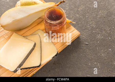 Eine Komposition aus italienischen Pecorino Käsescheiben mit Marmelade und Birnen auf ein Schneidbrett aus Holz Stockfoto