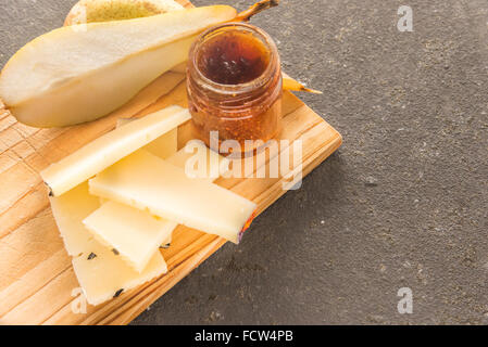 Eine Komposition aus italienischen Pecorino Käsescheiben mit Marmelade und Birnen auf ein Schneidbrett aus Holz Stockfoto