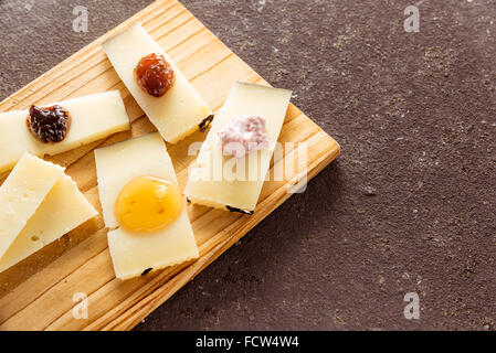 Eine Komposition aus italienischen Pecorino Käsescheiben mit Marmeladen von verschiedenen Geschmacksrichtungen auf ein Schneidbrett aus Holz Stockfoto