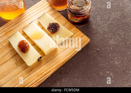 Eine Komposition aus italienischen Pecorino Käsescheiben mit Marmeladen von verschiedenen Geschmacksrichtungen auf ein Schneidbrett aus Holz Stockfoto