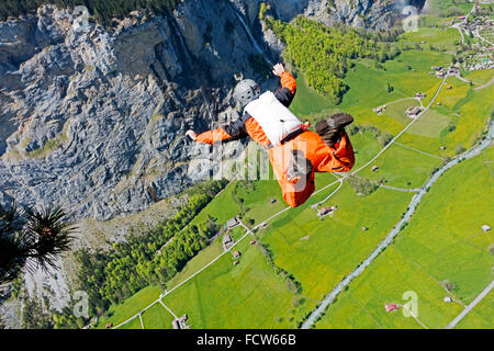 Mann in orange Sprunganzug ist von einer Klippe fallen. Bald hat er seinen Fallschirm zu öffnen, bevor Sie auf dem harten Boden! Stockfoto