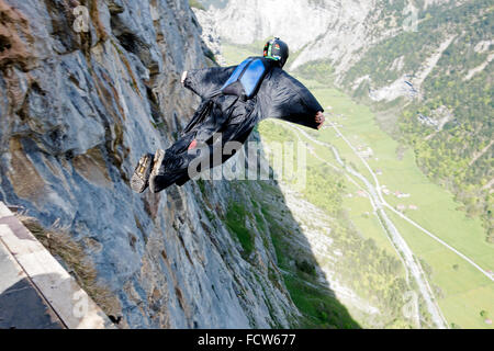 Mann in einem Anzug Birdman ist von einer Klippe springen. Dadurch ist er Stretch-out der Flügel und steigen entlang den Bergwänden. Stockfoto