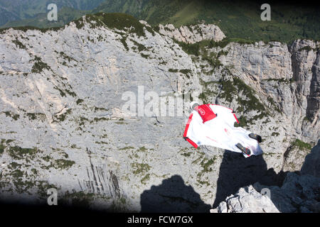 Crazy Base Jumper fliegen innerhalb seiner Wingsuit entlang einer Felswand. Dabei hat er die hochfliegenden mit 100 km/h vorwärts und hat einen grossen Ansturm. Stockfoto