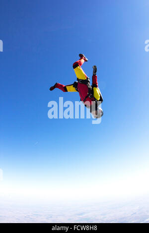 Eine Fallschirmspringer-Mädchen ist in einem kopfüber-Position in den blauen Himmel fliegen. Dadurch erhalten sie eine Geschwindigkeit bis zu 150 km/h nach unten. Stockfoto