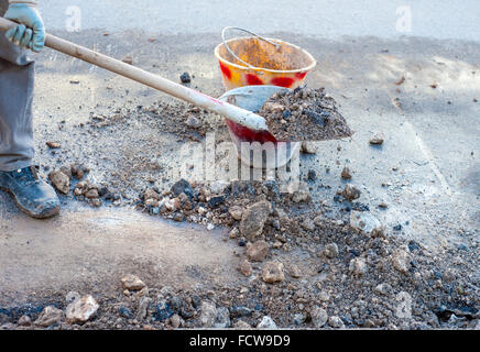 Arbeiter funktioniert mit Schaufel und Eimer Reinigung Schutt aus dem Weg, Stockfoto