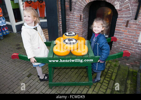 Kinder und Anzeige der Gouda-Käse auf einer traditionellen hölzernen Karren vor Henri Willig Shop, Amsterdam Holland Niederlande Stockfoto