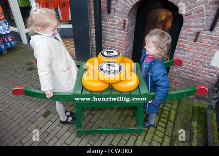 Kinder und Anzeige der Gouda-Käse auf einer traditionellen hölzernen Karren vor Henri Willig Shop, Amsterdam Holland Niederlande Stockfoto