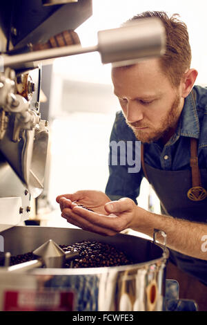 Blick auf gerösteten Kaffeebohnen aus einer Röstmaschine Mann Stockfoto