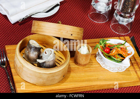 Geschirr, Holz Cup mit gedünstetem Fisch, Salat, Besteck Stockfoto