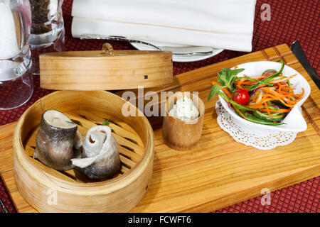 Geschirr, Holz Cup mit gedünstetem Fisch, Salat, Besteck Stockfoto