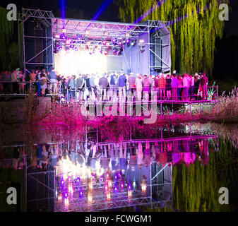 Menschen bei einem Konzert in der Nacht, im Wasser gespiegelt Stockfoto