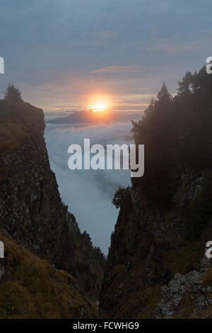 Sonnenuntergang im Dunst über den Wolken auf eine Wanderung über hohe Berge in den Schweizer Alpen zu sehen. Stockfoto