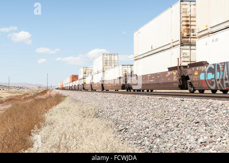 Zug, beladen mit Containern Ware rollt aber New Mexico Hochebenen Landschaften und Eisenbahn neben Route 66-Fokus-Punkt Stockfoto