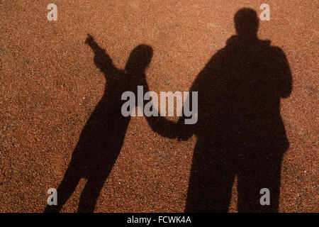 Schatten der Erwachsenen und jungen Mädchen Hand in Hand. Kleines Mädchen zeigt, Stockfoto
