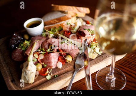 Eine mediterrane Board mit Schinken, Brot, Oliven, Artischocken, sonnengetrocknete Tomate und eingelegte Zwiebeln Stockfoto