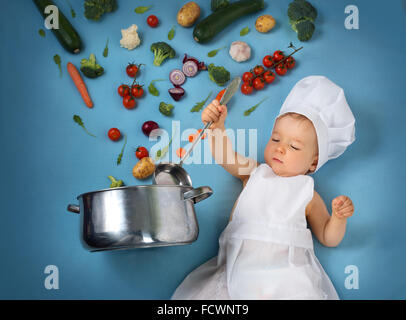 Baby Boy in Koch Hut mit Kochen Pfanne und Gemüse Stockfoto