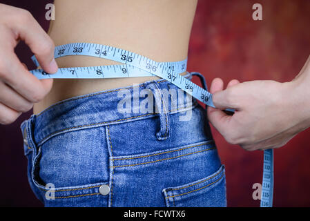 schlanke Asiatin, trägt Jeans, messen ihre Körperform, Taille, Gesäß Stockfoto