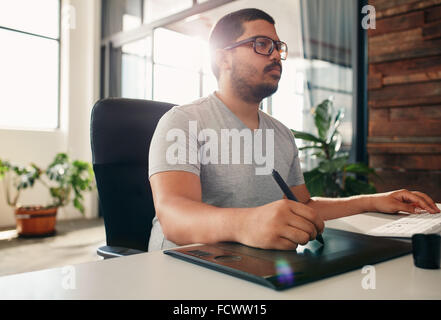 Porträt des jungen männlichen Foto-Editor bei der Arbeit in seinem Büro. Männliche Grafik-Designer arbeiten an seinem Schreibtisch mit digitalen grafischen Tabelle Stockfoto