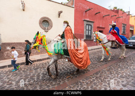 Die Heiligen drei Könige Reiten mit dem Pferd durch die Kopfsteinpflaster-Straßen verteilen Süßigkeiten an Kinder während El Dia de Reyes 6. Januar 2016 in San Miguel de Allende, Mexiko. Das traditionelle Fest markiert den Höhepunkt der zwölf Tage von Weihnachten und erinnert an die drei Weisen, die aus der Ferne gereist mit Geschenken für das Kleinkind Baby Jesus. Stockfoto