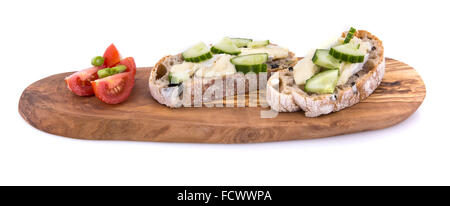 Gurke und Brie Sandwich auf Olivenöl Brot mit Tomaten und Frühlingszwiebeln auf einem Olivenholz Servierplatte über einem weißen Hintergrund Stockfoto