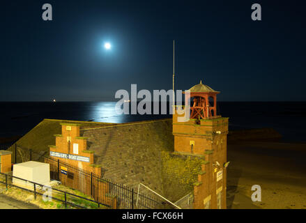 Cullercoats RNLI-Rettungsstation in der Nacht mit Vollmond über einem ruhigen Meer Stockfoto