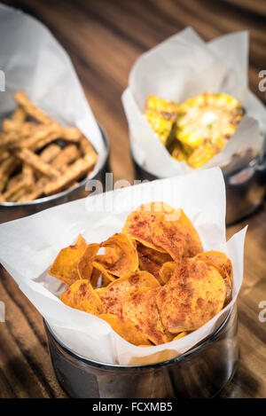 rustikale Kartoffel-Chips und anderen einfachen Snack Essen auf Tisch Stockfoto