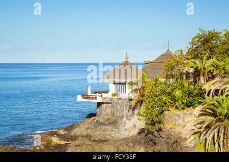 Teneriffa, Spanien - 14. Januar 2013: Hütten mit Strohdach am Rand einer Klippe am Meer am Strand Costa Adeje Teneriffa Stockfoto