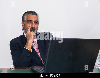 Geschäftsmann in Anzug und Krawatte, in seinem Atelier. Am Schreibtisch, mit pc. Stockfoto