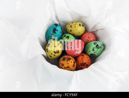 Ostern-Stillleben. Bunte Ostern Wachteleier auf einem weißen Papierhintergrund einwickeln. Stockfoto