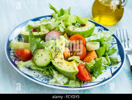 Frischer Salat mit Avocado, Tomaten, Salat, Radieschen, Karotten, Zwiebeln und Gewürzen Stockfoto