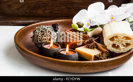 Wellness-Produkte in Holztablett mit weißen Orchideen und Duft Kerzen Stockfoto