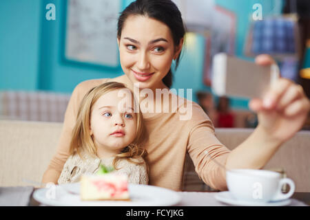 Junge Frau mit Tochter machen ihre Selfie im café Stockfoto