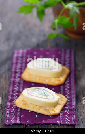 Scheiben Käse mit Schinken und Petersilie auf salzigen Keks Stockfoto