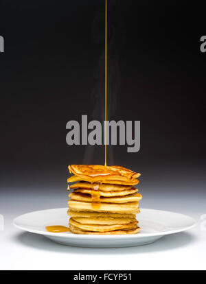 Stapel von Pfannkuchen auf weißen Teller beträufelt mit Sirup Stockfoto