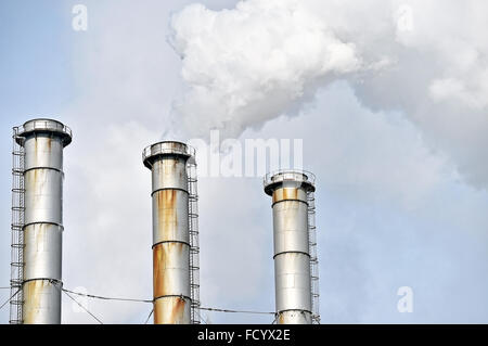 Rauch und Dampf, die sich aus einem petrochemischen Industrieanlagen Schornstein mit einem blauen Himmel im Hintergrund Stockfoto