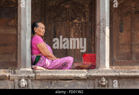 Alte Frau sitzt vor einem Tempel in Patan Stockfoto