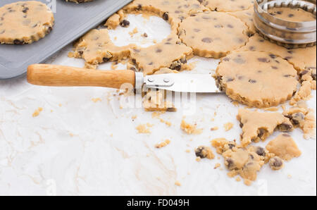 Cookies von raw chocolate Chip Teig schneiden und mit einem Spachtel auf ein Metall Backblech heben Stockfoto