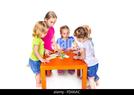 Glückliche Kinder spielen mit Rätseln, die isoliert auf weiss. Teamarbeit, Kreativität-Konzept. Stockfoto