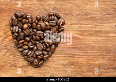 Kaffee Herzsymbol hergestellt aus gerösteten Körnern auf Vintage Holzoberfläche Stockfoto