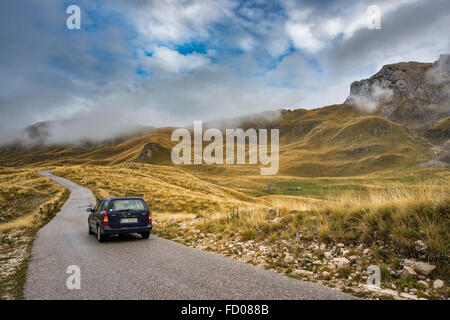 Fahrzeug auf Mountain Road, niedrige Wolken über Piva Plateau und Berge, Durmitor Nationalpark Durmitor, Dinarischen Alpen, Montenegro Stockfoto