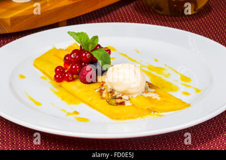 Schönen Pfannkuchen mit Honig und servieren Eis, verziert mit Nüssen, frischen Beeren. Stockfoto