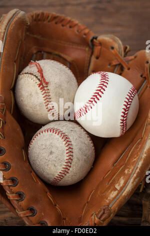 Zwei alte Baseballs und einen neuen Ball in einem Baseballhandschuh Stockfoto