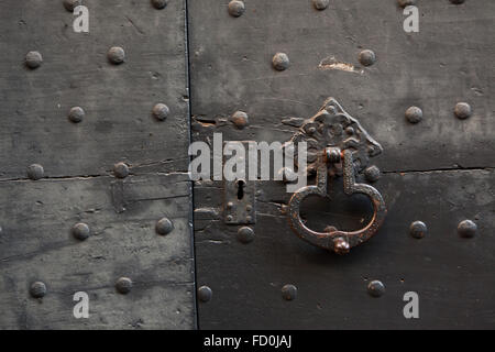 Alte Metall wundervollen auf den schwarz lackierten Holztor fixiert mit Nieten in Bergamo, Lombardei, Italien. Stockfoto
